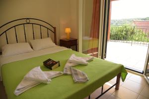 a bedroom with a bed with a green blanket and a balcony at Elia Village in Meganisi