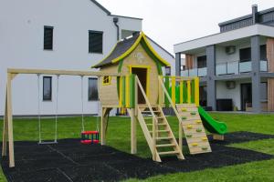 un parque infantil con tobogán y una casa en Apartmaji BANONIA " Poletni vetrc ", en Banovci