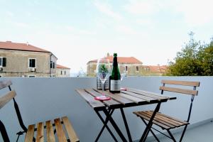 een tafel met 2 stoelen en een fles wijn op een balkon bij La Piazza in Umag