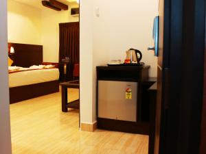 um quarto de hotel com uma cama e um pequeno frigorífico em Staylite Suites em Chennai