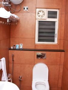a bathroom with a toilet and a window at Staylite Suites in Chennai
