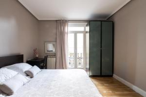 Un dormitorio con una gran cama blanca y una ventana en Downtown apartment en San Sebastián