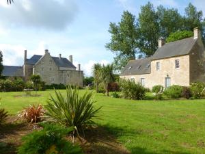 an old stone house with a grass yard at Le cottage de Savigny in Valognes