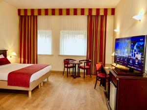 a hotel room with two beds and a television at Golden Tulip Hotel de’ Medici in Bruges