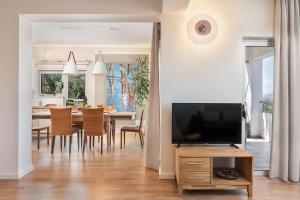 a living room with a television and a dining room at Anemone Holiday Apartment in Kato Daratso