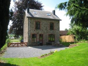 a large stone house with a wooden fence in a yard at A beautifully renovated mansion in the Ardennes in Vielsalm