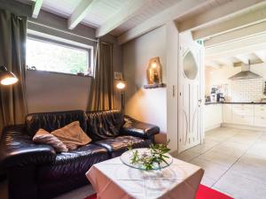 sala de estar con sofá de cuero y mesa en This accommodation is full of atmosphere and on a beautiful estate en Zedelgem