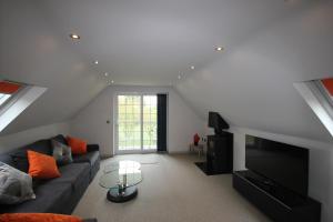 a living room with a couch and a television at Flintstone Cottages in Chichester