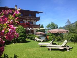 a house with two lawn chairs and an umbrella at Pension Hinterseer in Kitzbühel