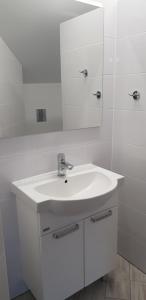 a white bathroom with a sink and a mirror at Siódme Niebo-komfortowe pokoje nad samym morzem in Stegna