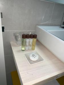 Un mostrador con tres botellas junto a una bañera. en Galerías 16 Viviendas Turísticas en Lugo