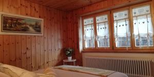 um quarto com paredes e janelas de madeira e uma cama em "Le Sorelle" Apartments em Ferden