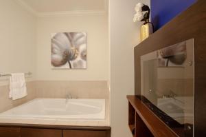 baño con bañera y una foto de una flor en Premiere Suites - St. John's Signal Hill Gate, en St. John's