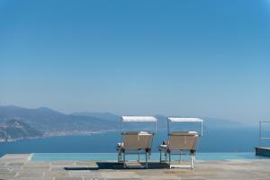 two chairs sitting on a patio overlooking the water at Il Leccio - Luxury Resort Portofino Monte in Santa Margherita Ligure