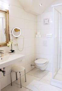 a white bathroom with a toilet and a sink at Stadthotel Restaurant Auerhahn in Vöcklabruck