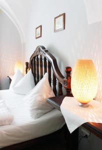 Una cama con sábanas blancas y una lámpara en un escritorio. en Stadthotel Restaurant Auerhahn, en Vöcklabruck