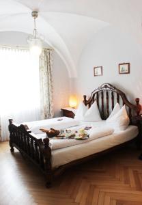 a bedroom with a large wooden bed with white sheets at Stadthotel Restaurant Auerhahn in Vöcklabruck