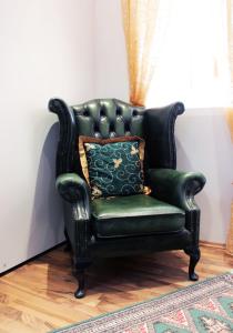 a green leather chair with a pillow in a room at Stadthotel Restaurant Auerhahn in Vöcklabruck