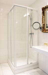 a glass shower in a white bathroom with a sink at Stadthotel Restaurant Auerhahn in Vöcklabruck