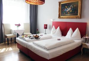 a bedroom with a large bed with a red headboard at Stadthotel Restaurant Auerhahn in Vöcklabruck
