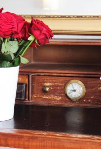 a vase of roses sitting next to a clock at Stadthotel Restaurant Auerhahn in Vöcklabruck