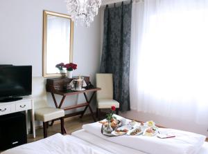 a room with a bed with a table and a tv at Stadthotel Restaurant Auerhahn in Vöcklabruck