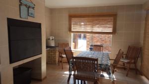 a dining room with a table and chairs and a television at Hartenbos huisie in Hartenbos