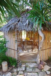 a small hut with a table and a palm tree at Cottage sul lago - Officina Didattica in Donnalucata