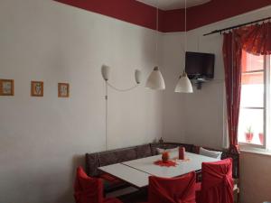 a dining room with a white table and red chairs at Apartment Majda in Lendava