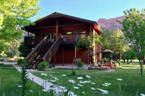 a log cabin with a porch and flowers in the yard at Castle Valley Inn in Moab