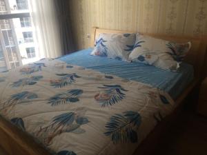 ein Bett mit einer blauen und weißen Decke und einem Fenster in der Unterkunft Capitalland's Service Apartment Park 7 Vinhomes in Ho-Chi-Minh-Stadt