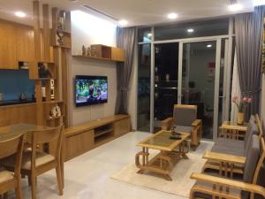 ein Wohnzimmer mit einem TV, einem Tisch und Stühlen in der Unterkunft Capitalland's Service Apartment Park 7 Vinhomes in Ho-Chi-Minh-Stadt