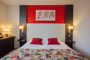 een slaapkamer met een bed met 2 rode kussens bij The Originals Boutique, Hôtel Le Pillebois, Bourg-en-Bresse Nord in Malafretaz