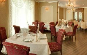 a dining room with white tables and red chairs at Purple Star Apartments in Saints Constantine and Helena