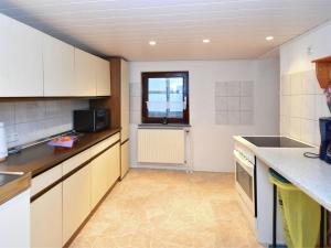 una cocina con armarios blancos y una ventana en Small apartment in Hesse with terrace and garden, en Frielendorf