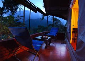 2 sillas y mesa en un balcón con vistas en Grassroots Wayanad, Valley-view Tents, en Vythiri