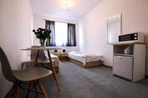 Habitación pequeña con cama y mesa con un jarrón de flores en Apartamenty Południowa, en Szczecin