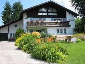 una casa con un jardín de flores delante de ella en Gästehaus Alpenland, en Halblech