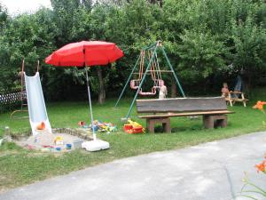 un parque con banco, sombrilla y parque infantil en Gästehaus Alpenland, en Halblech