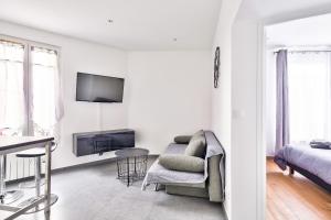 a white living room with a couch and a tv at The Pearl Suite in Vitry-sur-Seine