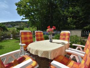 a table with four chairs and a vase of flowers at Attractive Bungalow in Ilsenburg with Private Terrace in Ilsenburg