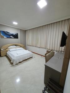 a hotel room with a bed and a desk and a desk at Guaratur Hotel in Linhares