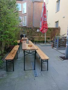 a row of wooden tables and benches with an umbrella at Backpackers St. Pauli in Hamburg