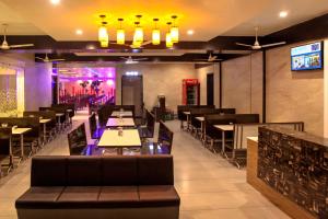 a restaurant with tables and chairs and a bar at Hotel Fun City in Navsāri