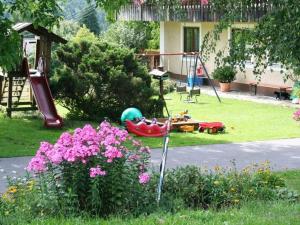 un jardín con parque infantil con tobogán y flores en Holiday home with garden near the forest, en Arnschwang