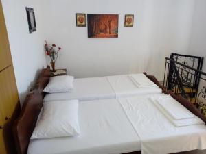 2 camas en una habitación con sábanas blancas en Garden Of Olive Trees en Asfendhilés