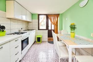 a kitchen with green walls and white cabinets and a table at Apartment Ante in Umag