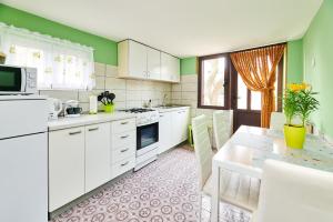 a kitchen with white cabinets and green walls and a table at Apartment Ante in Umag