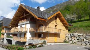 ein großes Holzhaus mit Balkon auf einem Hügel in der Unterkunft 63 Route du Rochas in Vaujany