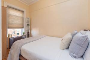 een slaapkamer met een wit bed met kussens en een raam bij Lavish 3 Bedroom Apt in Williamsburg!! in Brooklyn
